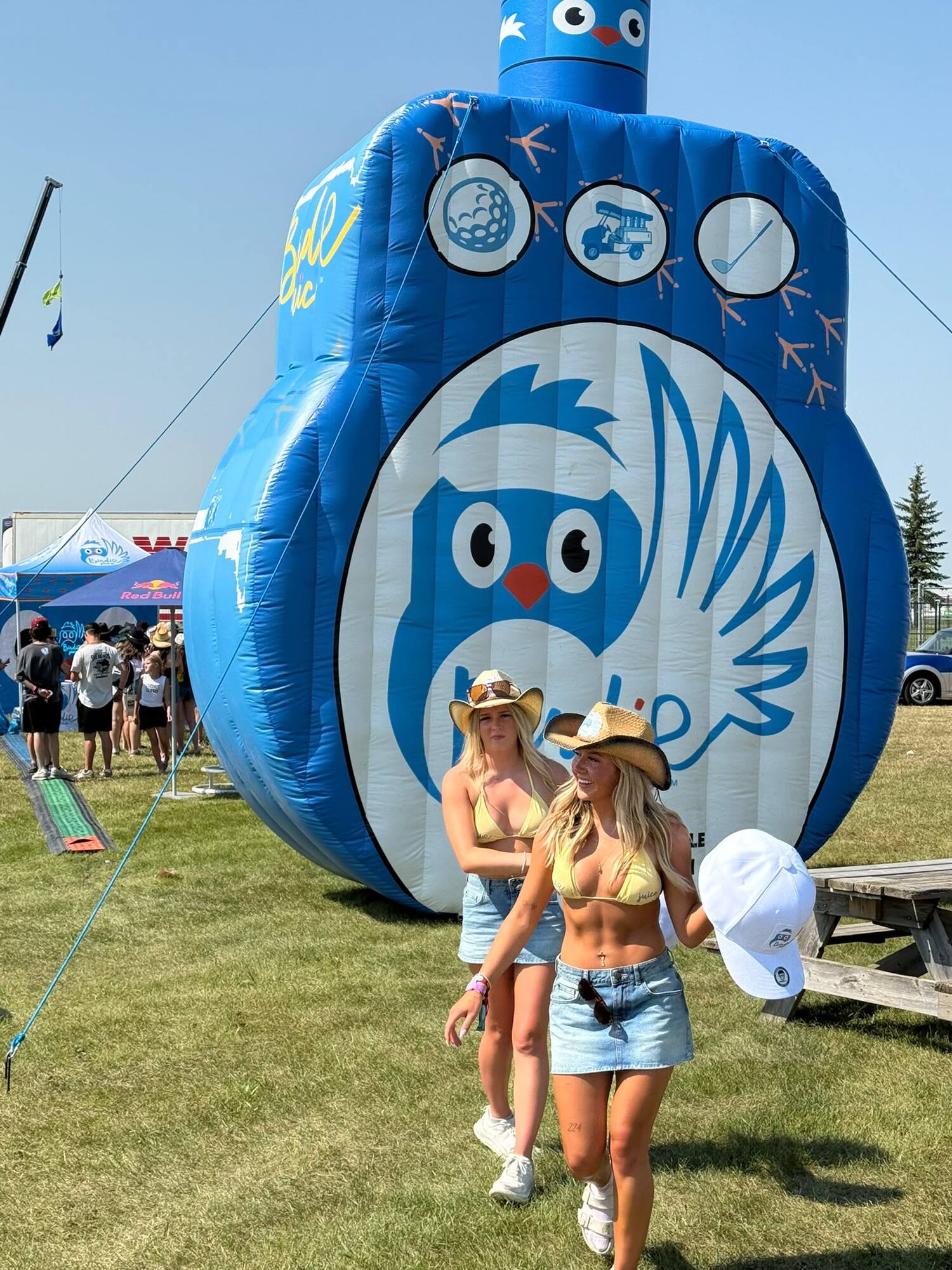 A giant inflatable Birdie Juice bottle towering over the festival grounds as two guests walk past